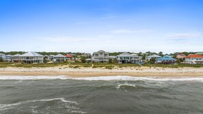 A beachfront property with multiple houses, a sandy beach, and the ocean.