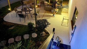 Une terrasse extérieure équipée d’un barbecue, d’un espace salon et de guirlandes lumineuses.