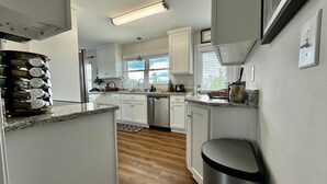 Une cuisine moderne avec des meubles blancs, une poubelle en acier inoxydable et un plan de travail en granit.