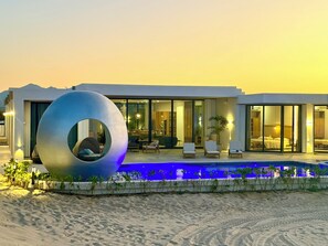 Un hotel moderno con piscina, una gran escultura circular y un paisaje desértico.