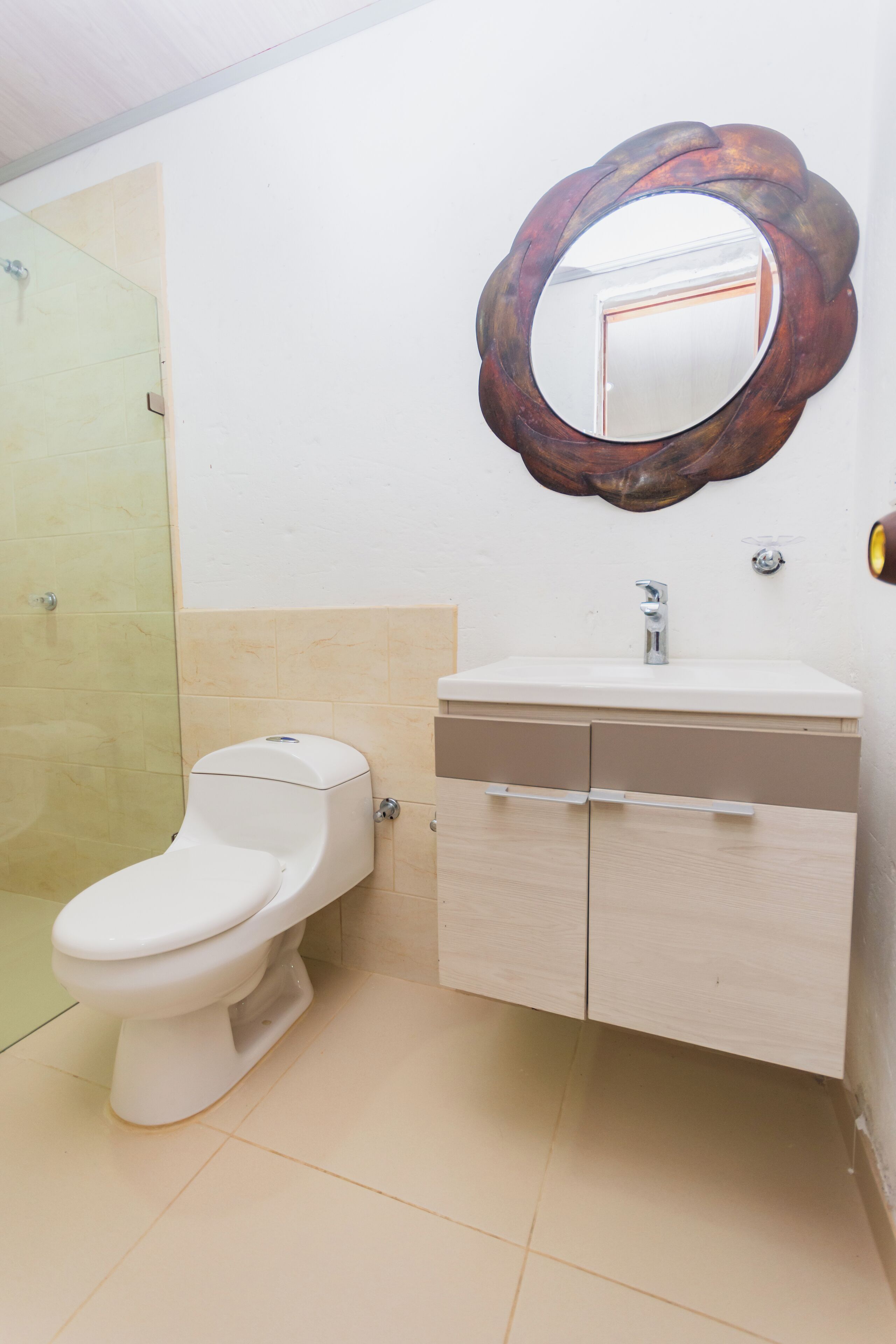 Et badeværelse med toilet, håndvask og spejl.
