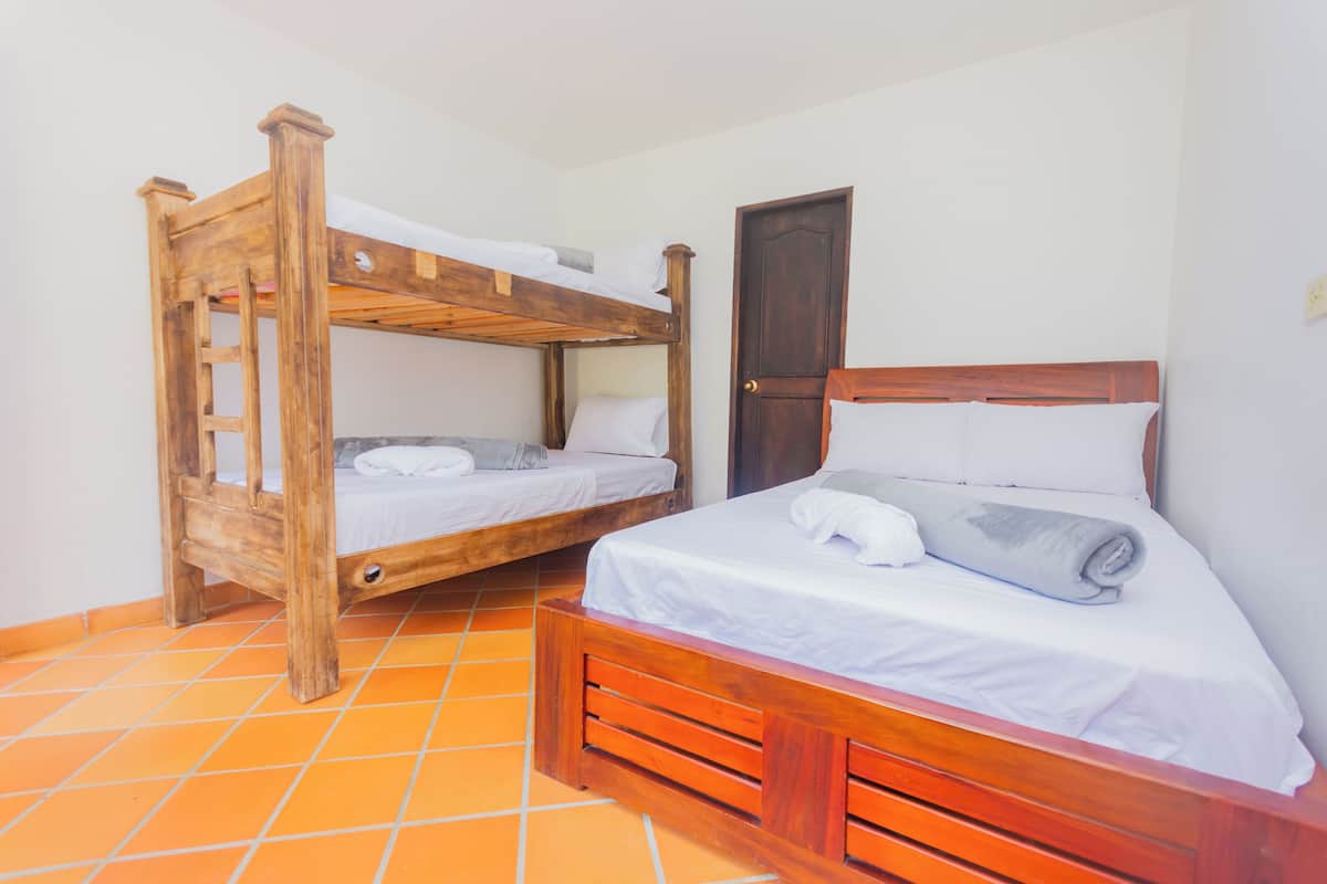A room with two wooden bunk beds, a door, and orange-tiled flooring.