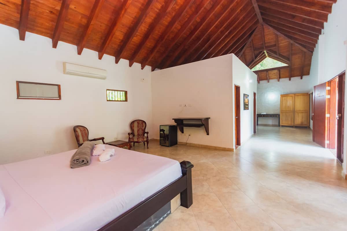 A bedroom with a wooden ceiling, a bed, a chair, a desk, and a wardrobe.