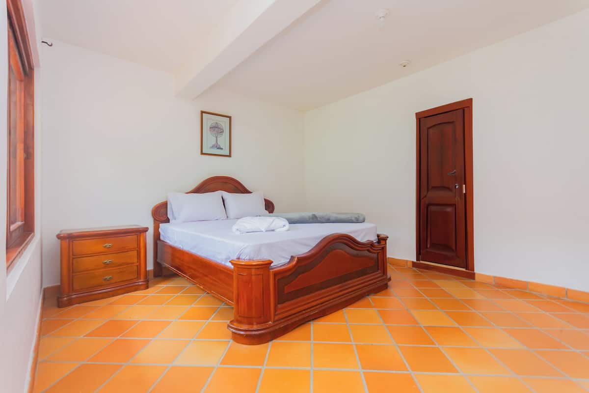 A bedroom with a wooden bed, a nightstand, and a door.