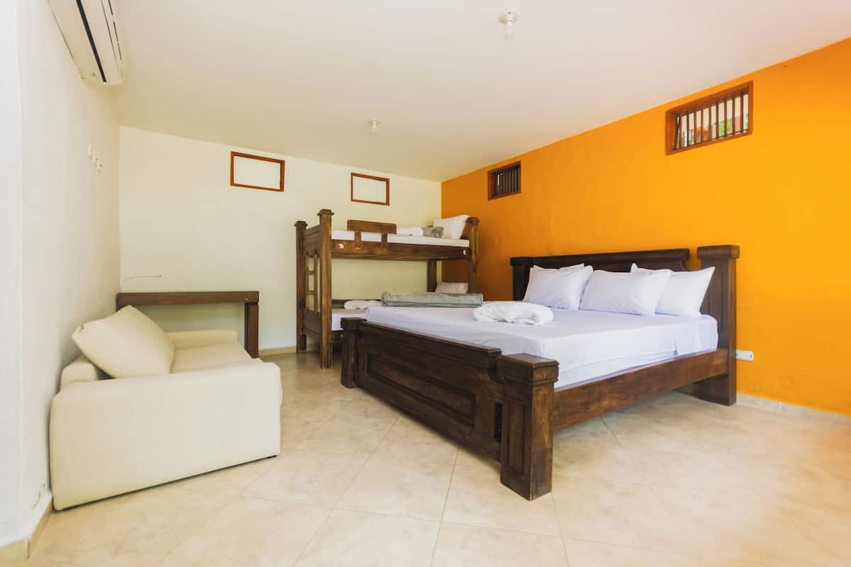 A bedroom with a bunk bed, a sofa, and a bedside table.