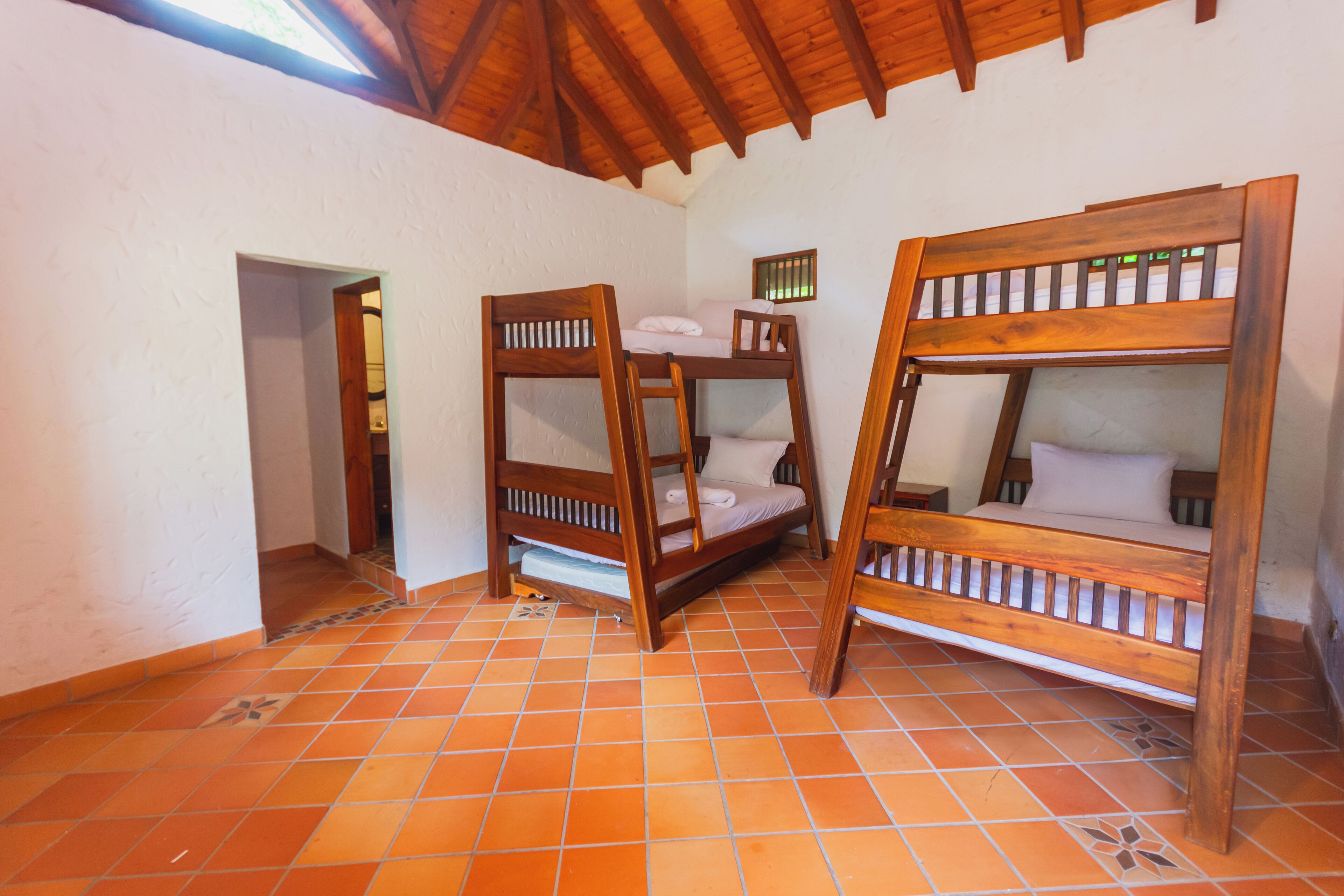 A room with three wooden bunk beds, a tiled floor, and a sloped ceiling.