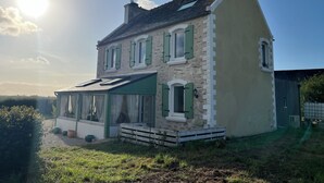 Et toetagers hus med skråtag, grønne skodder og en synlig skorsten.