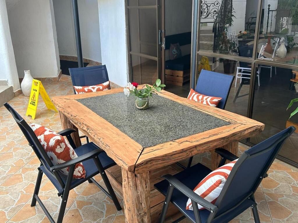 A wooden table with a glass top surrounded by chairs with patterned cushions.
