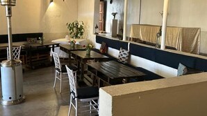 A cozy cafe with wooden tables and chairs, a large mirror, and a hanging light fixture. - Enkishon Suites - 13 (Kiambu County)