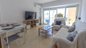 A living room with a dining table set for four, a sofa, a coffee table, and a television.