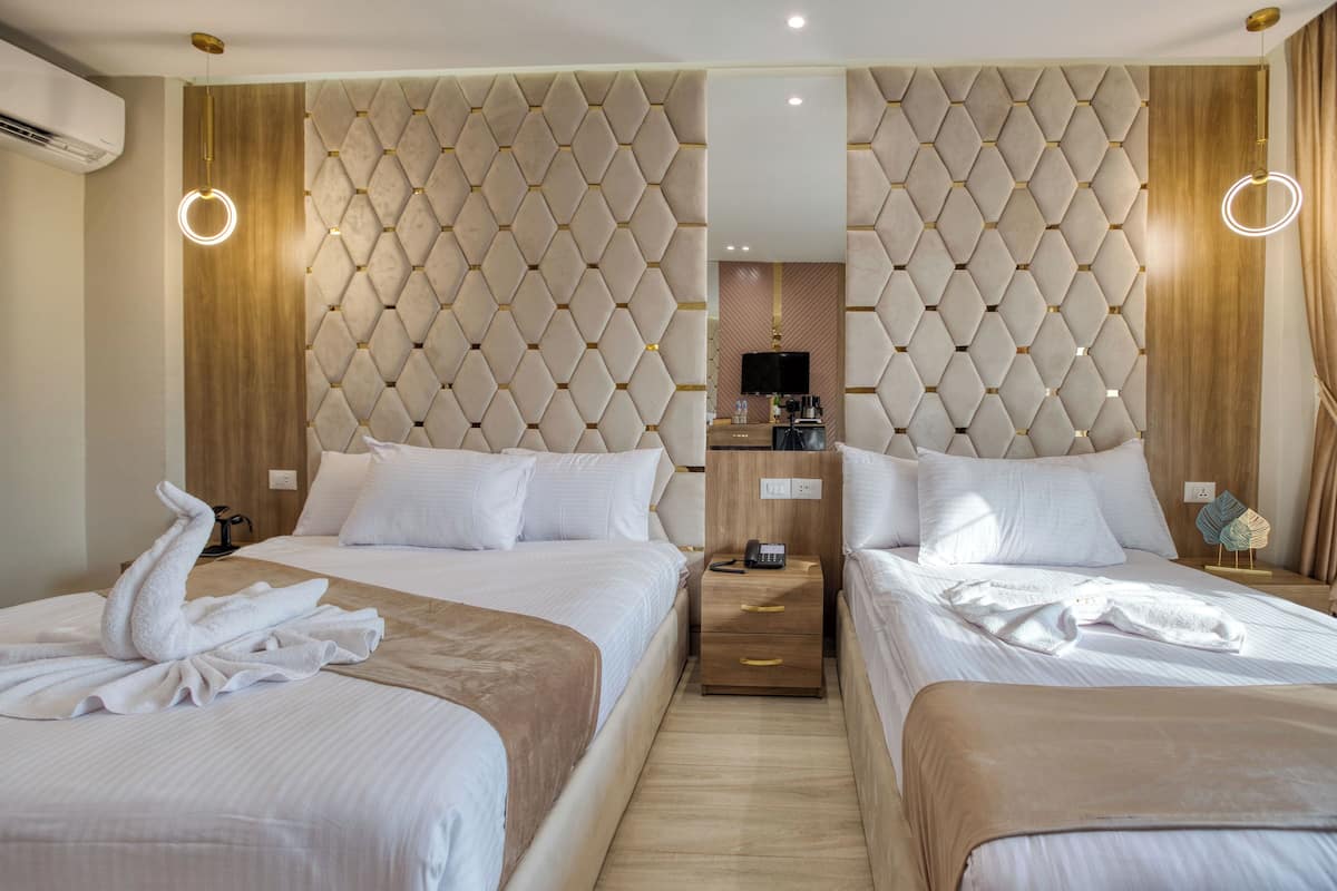 Une chambre d’hôtel avec deux lits, une table de chevet en bois, une télévision et un miroir.