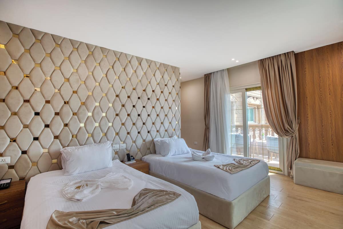 Une chambre d’hôtel avec deux lits, une tête de lit moderne, un plancher en bois et une vue sur l’extérieur.