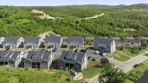 A residential area with modern houses, a parking lot, and a green landscape in the background. - Luxury Condo / Pool / Game Room / Grill / Pets (Branson)