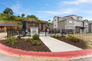 A residential area with a swimming pool, a covered patio, and a fenced garden area. - Luxury Condo / Pool / Game Room / Grill / Pets (Branson)