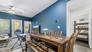 A room with a wooden dining table, benches, a ceiling fan, and a bunk bed. - Luxury Condo / Pool / Game Room / Grill / Pets (Branson)