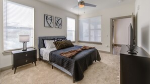 A bedroom with a bed, bedside tables, a ceiling fan, and a television.