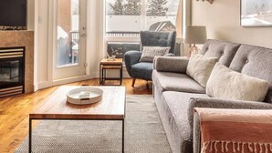 A living room with a sofa, armchair, coffee table, and fireplace.