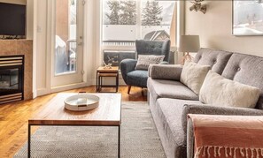Una sala de estar con sofá, sillón, mesa de centro y chimenea.