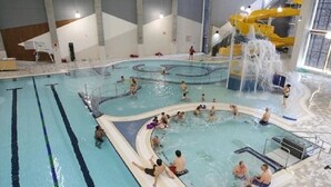 Une piscine intérieure dotée de plusieurs couloirs de nage, d’un toboggan et d’une zone de jeux peu profonde.