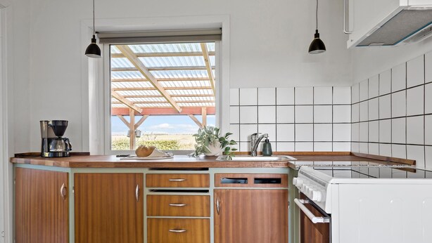 A kitchen with wooden cabinets, a built-in oven, a sink, and a window with a view of greenery. - Awesome home in Tønder with WiFi (Tønder)