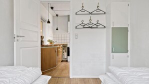 A modern, minimalist bedroom with two beds, a wooden floor, and a kitchen in the background. - Awesome home in Tønder with WiFi (Tønder)