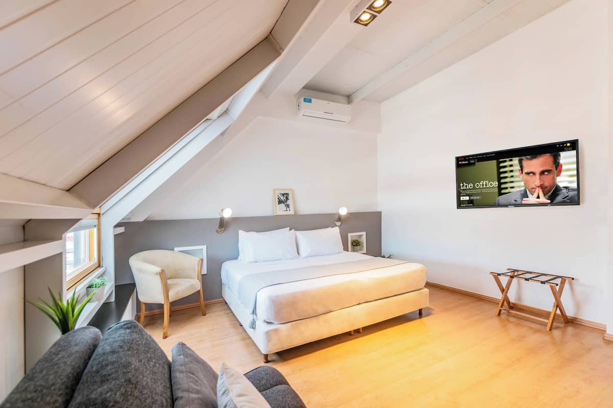 A modern bedroom with a bed, a chair, a TV, and a small table.