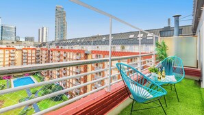A balcony with a view of a cityscape, a small pool, and blue chairs. - Modern Lofts in Puerto Madero (Buenos Aires)