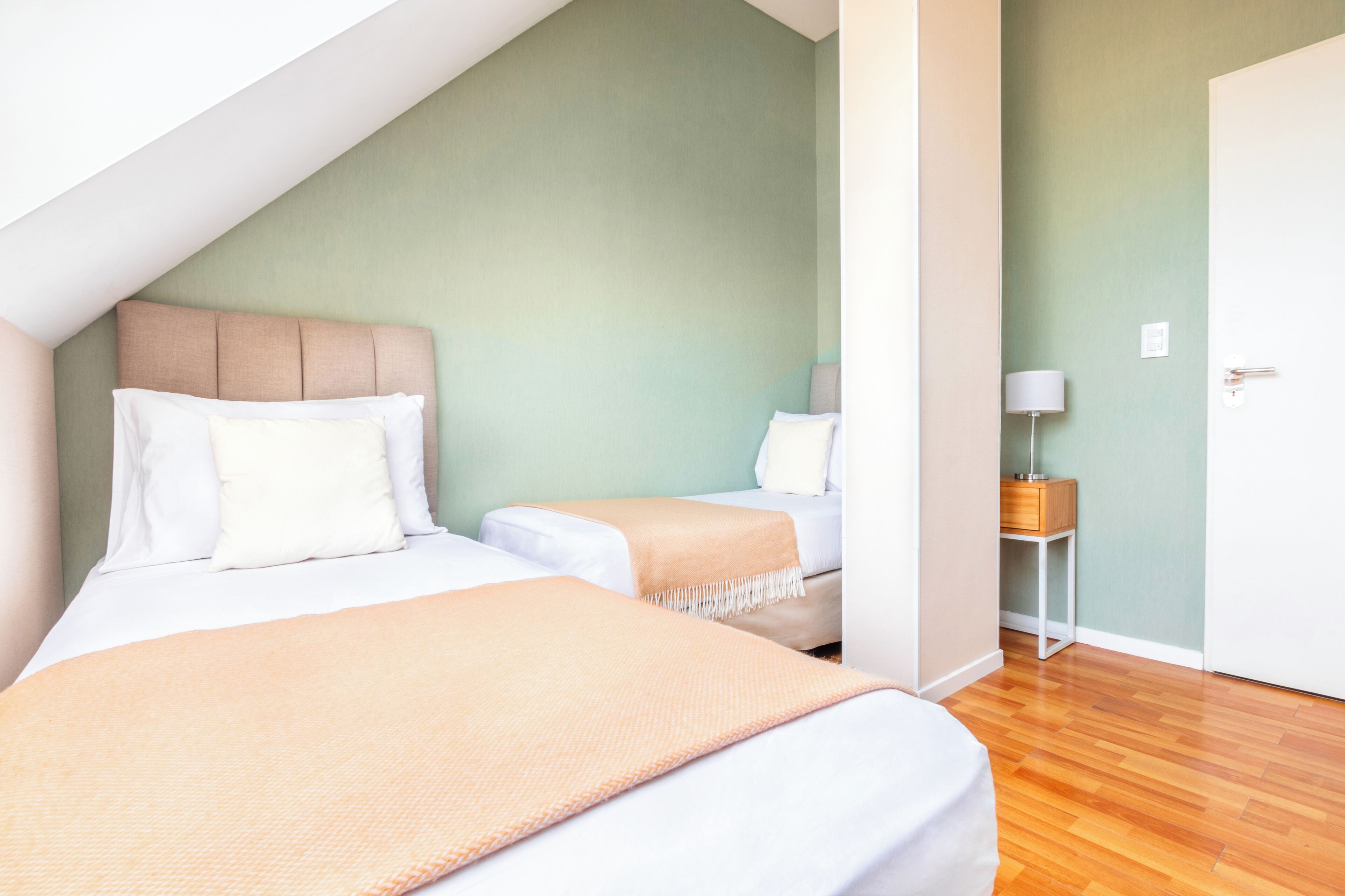 Ein Schlafzimmer mit zwei Betten, Holzboden und einer Tür.