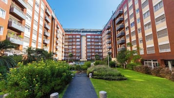 Un edificio residencial de varios pisos con balcones, un patio central y abundante vegetación alrededor.