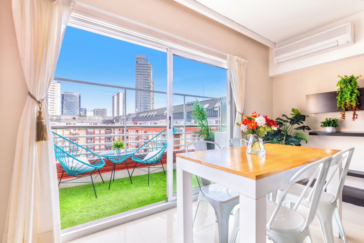 A modern apartment with a balcony, a dining table, and chairs.