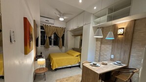 Une chambre à coucher de taille réduite, comprenant un lit, une table de chevet et un petit espace bureau avec une chaise.