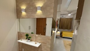 Une salle de bain moderne avec un lavabo blanc, deux appliques murales et un miroir.