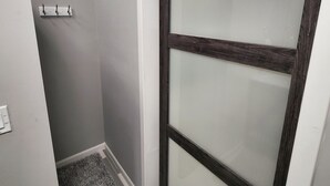 A narrow hallway with a frosted glass door, a small shelf with hooks, and a textured rug on the floor. - Cozy spot near Lake Winnie, studio in Rossville, WiFi, AC and privacy (Rossville)