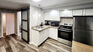 A modern kitchen with white cabinets, stainless steel appliances, and a wooden floor. - Cozy spot near Lake Winnie, studio in Rossville, WiFi, AC and privacy (Rossville)
