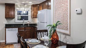 Une cuisine moderne avec des meubles en bois, un réfrigérateur blanc et une table à manger pour quatre personnes.