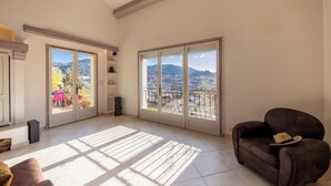 Un ampio soggiorno con ampie finestre che si affacciano sulla città, un divano marrone e un pavimento piastrellato.