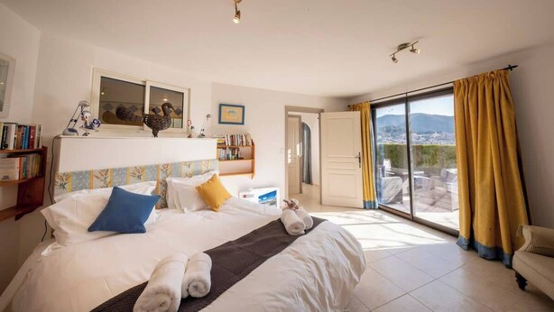 Una camera d'albergo con un letto, un comodino, una libreria, una finestra con tende e vista sull'esterno.