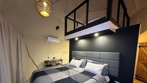 Ein modernes Schlafzimmer mit kariertem Bettbezug, einem Nachttisch mit Lampe und einem Deckenventilator.