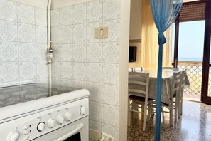 A kitchen with a stove, a power outlet, and a switch on the wall.