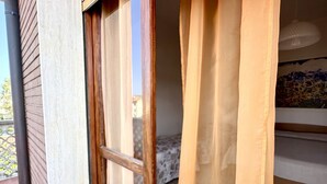 Una habitación con cama, ventana con cortinas y vistas al exterior.