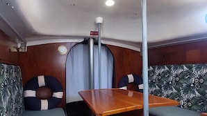 A compact cabin with a wooden table and benches, a ceiling light, and a small window.