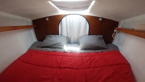 A small, cozy room with a bed, a window with curtains, and a skylight.