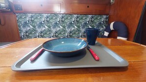 A dining table with a blue bowl and a red-handled spoon on a gray tray.