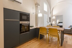 Une cuisine compacte équipée d’un four à micro-ondes, d’un four traditionnel et d’un coin repas avec des chaises et une table.