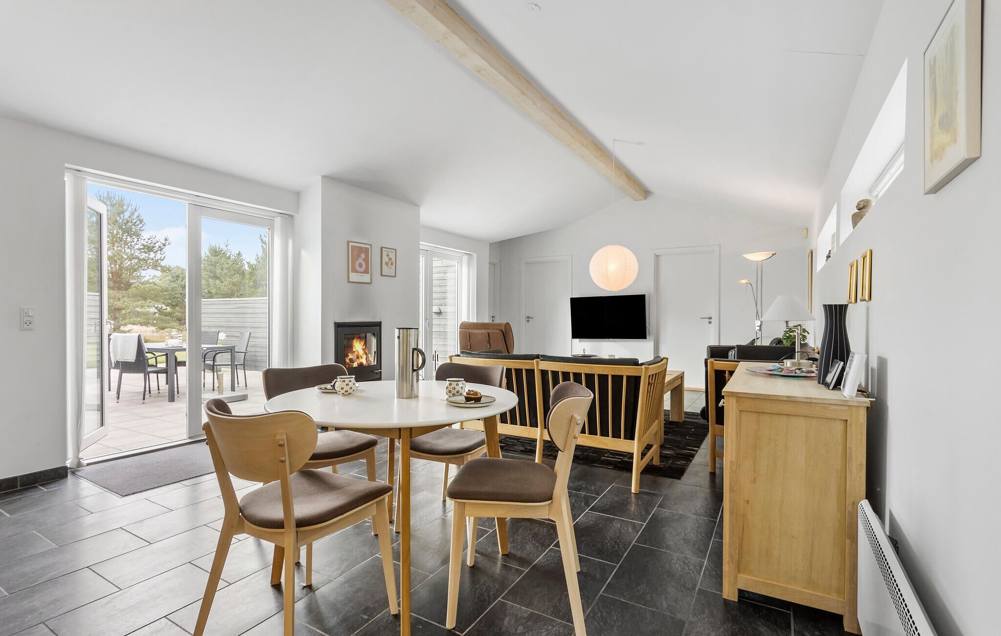 A modern kitchen with a central island, a dining area with wooden chairs, and a large window providing a view of the outdoors.
