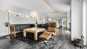 A modern living room with a black leather sofa, a wooden coffee table, and a brown leather chair. - 4 bedroom cozy home in ålbæk (Ålbæk)