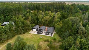 A modern two-story house with a large garage, surrounded by dense forest. - 4 bedroom cozy home in ålbæk (Ålbæk)