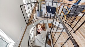 A spiral staircase with a metal railing leading to a living area with a sofa and a coffee table. - Colorado's Best (Colorado Springs)