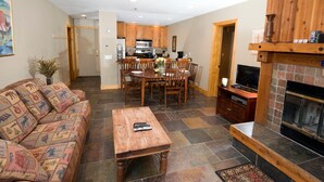 A living room with a sofa, coffee table, fireplace, and a dining area with chairs and a table.