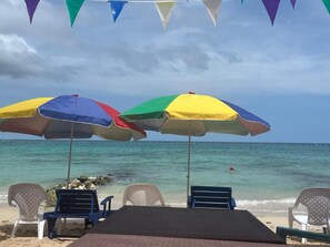 Aan een privéstrand, wit zand, ligstoelen, parasols